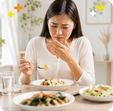 Woman looking uncomfortable at a dining table Foodintolerance.png